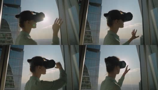 虚拟现实概念-年轻女子使用虚拟现实头盔对着摩天大楼的窗户高清在线视频素材下载