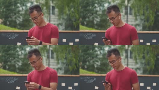 英俊的亚洲商人正在使用智能手机和耳机，与朋友交谈时，蓝牙耳机音频信息语音识别，人工智能助手高清在线视频素材下载