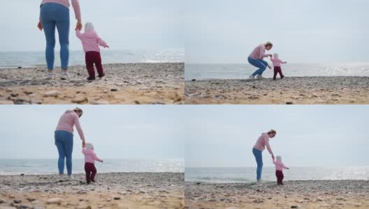 一位母亲牵着孩子的手向大海走去。户外散步。实时高清在线视频素材下载