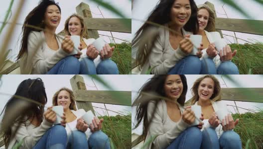 笑着多民族的女孩喝咖啡秋天海滩高清在线视频素材下载