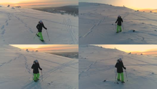 AERIAL:活泼的年轻女子在夕阳下穿着雪鞋走下雪坡高清在线视频素材下载