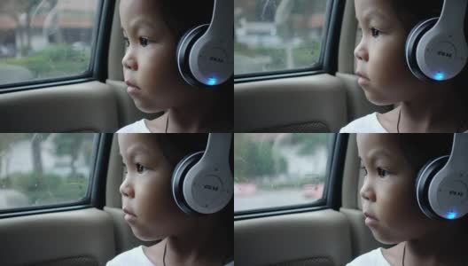 亚洲漂亮的女孩听音乐耳机移动在汽车和看在雨天高清在线视频素材下载