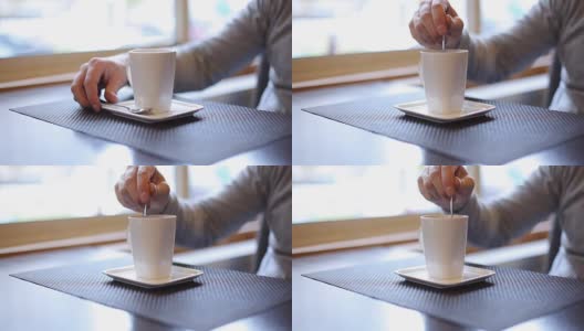 男子拿着勺子在高茶杯里搅拌热饮，近距离拍摄高清在线视频素材下载