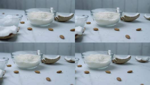 玻璃碗中近距离的椰子巧克力配料:干燥的椰子，枫糖浆，椰子黄油，装饰杏仁，椰子片。突出食物配料的概念。高清在线视频素材下载