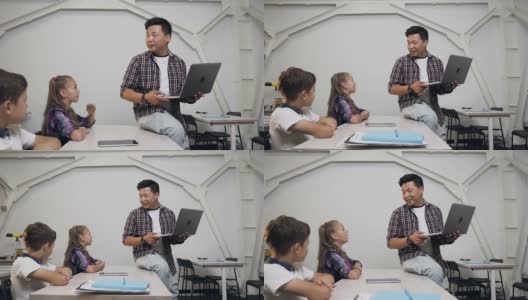 在学校上课时，可爱的白人女学生和同学坐在桌子后面，举手向韩国老师提问高清在线视频素材下载