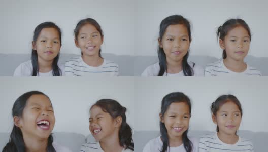 放大两个亚洲小女孩在客厅里看着相机，微笑着，幸福地一起笑。慢动作50 FPS。高清在线视频素材下载