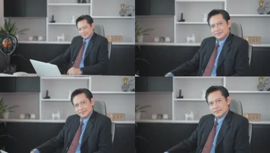 照片中的亚洲最高经理坐在办公室里，微笑着看着镜头高清在线视频素材下载