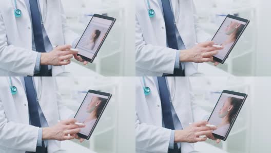 整形/整容外科医生手持数字平板电脑，屏幕上显示了各种类型的面部拉皮，前额拉皮，颧骨和鼻子矫正程序可供女性使用。高清在线视频素材下载