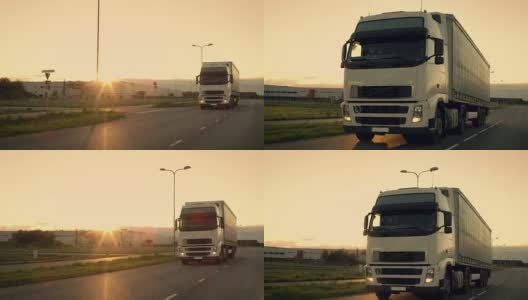 前视摄像头跟踪半卡车与货运拖车在高速公路上行驶。他在夕阳的背景下快速穿过工业仓库。高清在线视频素材下载