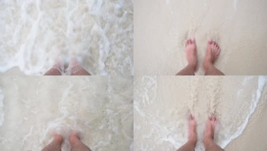 俯视图亚洲男人的脚站在沙滩上，海浪过来。高清在线视频素材下载