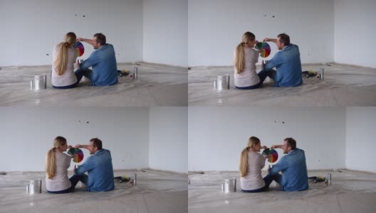 一对拉丁美洲夫妇坐在地板上为他们新家的墙壁选择颜色高清在线视频素材下载