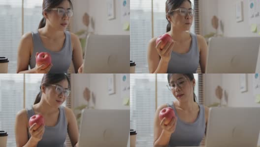 年轻健康的女性一边吃苹果一边用手机高清在线视频素材下载