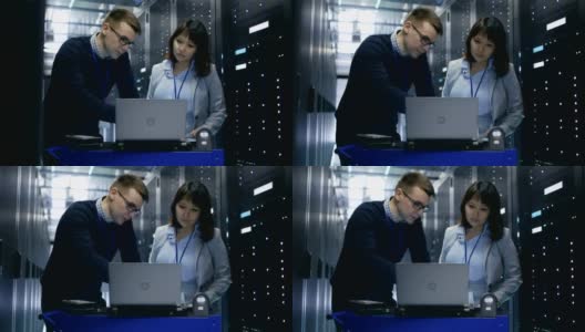 一名男性IT专家向一名女性服务器技术员展示笔记本电脑上的信息。他们正站在数据中心。高清在线视频素材下载