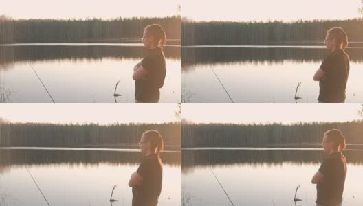 池塘上的渔夫。一个戴眼镜的年轻人穿着t恤钓鱼竿。高清在线视频素材下载