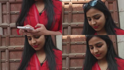 印度拉贾斯坦邦一名年轻女子手持手机微笑，用手机发短信打电话高清在线视频素材下载