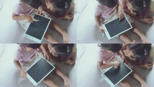 孩子坐在床上用数码板画画。高清在线视频素材下载