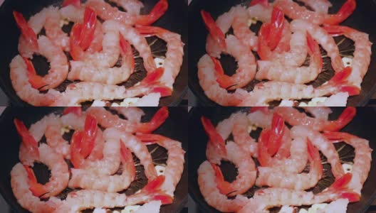 生虾在平底锅里烤在黑色背景。新鲜海鲜食材-虾尾即可烹煮，无需腌料。虾在锅里高清在线视频素材下载