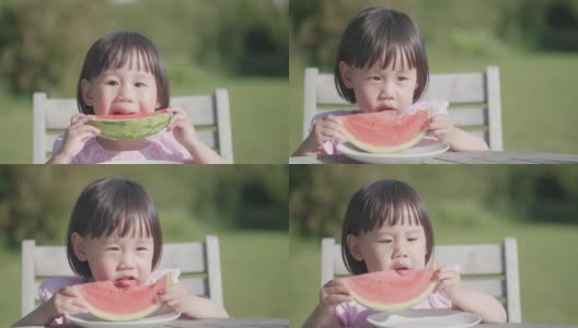 蹒跚学步的小女孩在夏天的家花园里吃西瓜高清在线视频素材下载