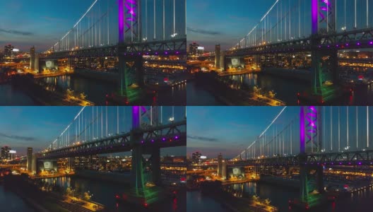 照明费城市中心，本杰明富兰克林桥和码头在老城在特拉华河晚上。无人机视频与下降的摄像机运动。高清在线视频素材下载