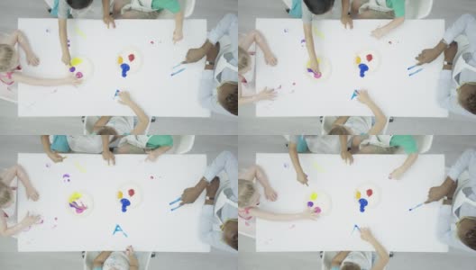一群孩子在干净的白色桌子上画手指画高清在线视频素材下载