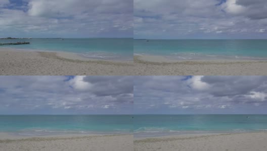 在一个多云的日子沿着格雷斯湾，普罗维登夏莱斯，特克斯和凯科斯群岛的海滩高清在线视频素材下载