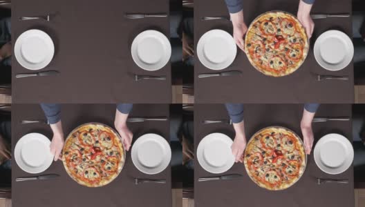 在披萨店，男性的双手正把一盘美味的披萨放到桌子上。传统意大利美食概念高清在线视频素材下载