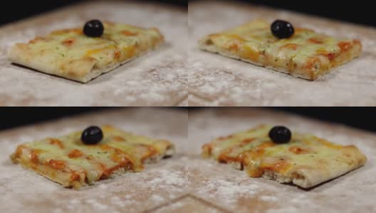 平面包披萨由奶酪和黑橄榄在砧板上与面粉在黑色的背景缓慢旋转高清在线视频素材下载