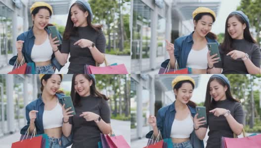 微笑年轻的亚洲女人与购物彩袋在商场背景。用智能手机在网上购物，站在商场大楼里微笑。生活方式的概念。慢镜头4 k。高清在线视频素材下载