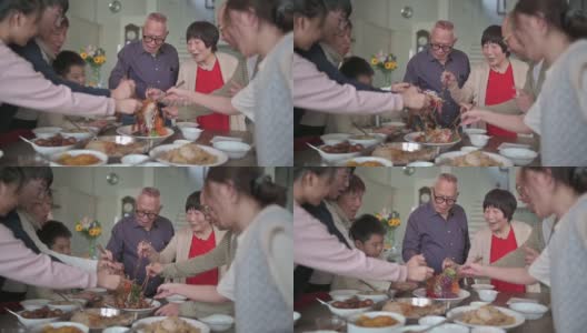 亚洲华人多代家庭庆祝中国新年前夕与传统食物娄桑(生鱼菜肴)团圆饭高清在线视频素材下载