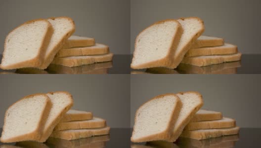 黑色的桌子上放着切片的新鲜面包。资料片。近距离的烤白切面包片躺在灰色的背景，食物的概念高清在线视频素材下载