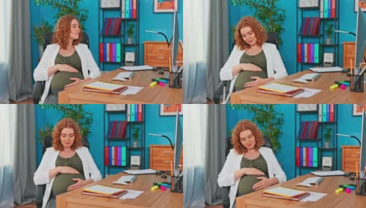 公司的领导坐在公司办公桌后面的转椅上，女人抚摸着，抚摸着，看着她怀孕的肚子，她微笑着，开心，不休息只是工作，没有产假高清在线视频素材下载