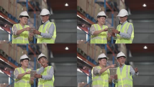 亚洲华人管理人员在仓库用数码桌子与白色安全帽反光服装进行讨论高清在线视频素材下载