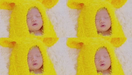 快乐的新生儿断奶可爱的黄色鸡蛋服装躺在灰色的地毯背景睡觉舒适和安全。可爱的亚洲婴儿在婴儿床上睡觉和打盹。新生儿复活节概念高清在线视频素材下载