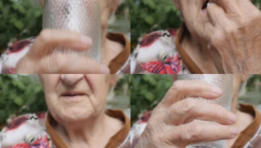 老妇人吃着药，喝着水。奶奶把药片放进嘴里。医疗保健和医疗理念。特写慢动作高清在线视频素材下载