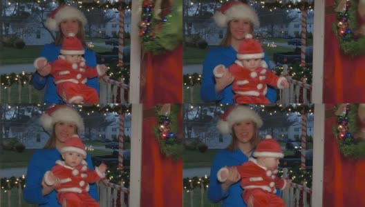 一位年轻的白人妈妈抱着一个婴儿，从前门走进一所装饰过圣诞节的房子高清在线视频素材下载