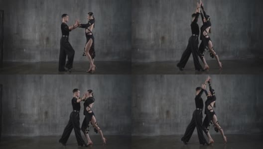 这对年轻的千禧一代舞蹈夫妇身穿黑色礼服，在摄影棚背景下以性感的姿势跳舞。高清在线视频素材下载