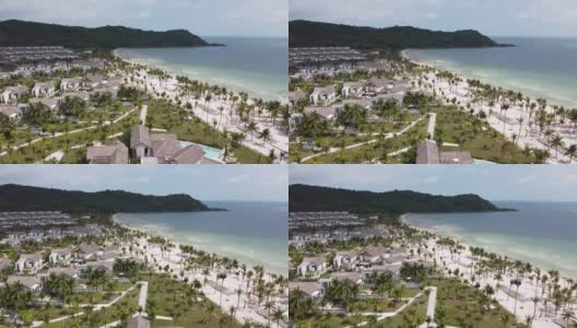 鸟瞰图蓝色的海洋在一个岛屿上的白沙，一个度假村与酒店和棕榈树高清在线视频素材下载