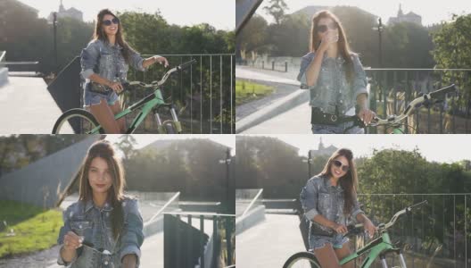 可爱快乐性感的女人穿着牛仔裤迷人的衣服和时尚的眼镜坐在自行车上，看着相机上的城市景观高清在线视频素材下载