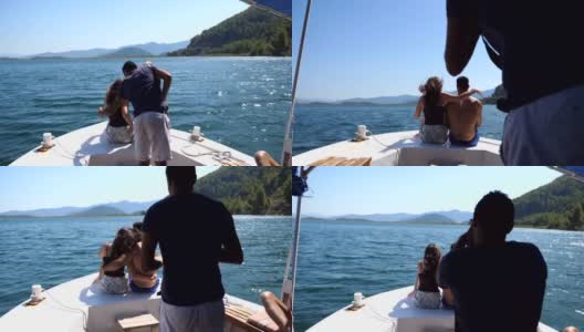 一对年轻的情侣坐在船头，对着不认识的摄影师摆姿势。幸福的情侣在船上共度时光，享受夏天的旅行。假期的概念。高清在线视频素材下载