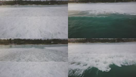 无人机摄像机跟随巨大的蓝色海洋泡沫海浪冲到美丽的异国度假胜地海岸热带树木和房屋高清在线视频素材下载