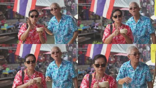 亚洲老年夫妇赴泰国水上市场旅游高清视频。喝新鲜椰汁高清在线视频素材下载