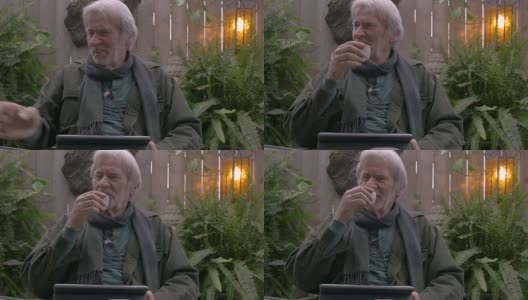 快乐的退休男子笑着喝着米酒用他的数字平板电脑高清在线视频素材下载