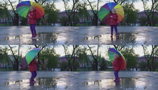 可爱的小女孩拿着五颜六色的雨伞在夕阳下的公园里的水坑里跳跃。高清在线视频素材下载