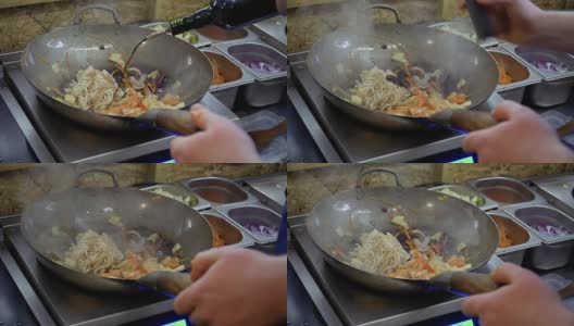 厨师将酱油和红烧酱倒入乌冬面和平底锅里炒的蔬菜中高清在线视频素材下载