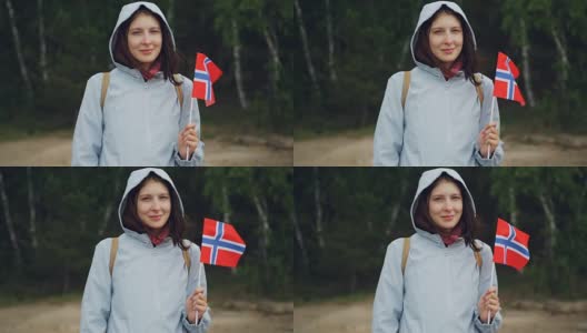 慢动作肖像迷人的挪威体育迷挥舞挪威官方旗帜站在森林和微笑。人、民族、国家观念。高清在线视频素材下载