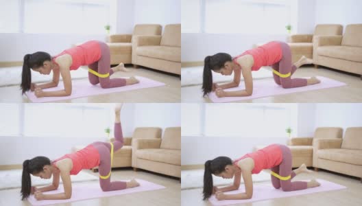 亚洲妇女在家瑜伽垫上锻炼。她使用橡胶阻力姿势“平板弯曲腿”。高清在线视频素材下载