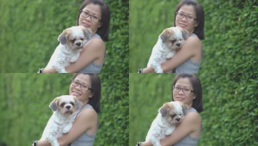 亚洲妇女拥抱她的狗在户外在家里高清在线视频素材下载