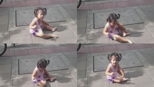 亚洲小女孩在人行道上哭，右手拿着钞票高清在线视频素材下载