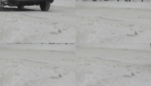 在冬天的城市里，汽车行驶在白雪覆盖的道路上。降雪。慢动作的车轮特写。轮胎面。恶劣的天气条件，交通，暴风雪。危险之旅高清在线视频素材下载