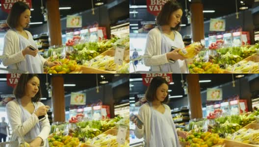 pregnant woman shopping in supermarket and using phone高清在线视频素材下载